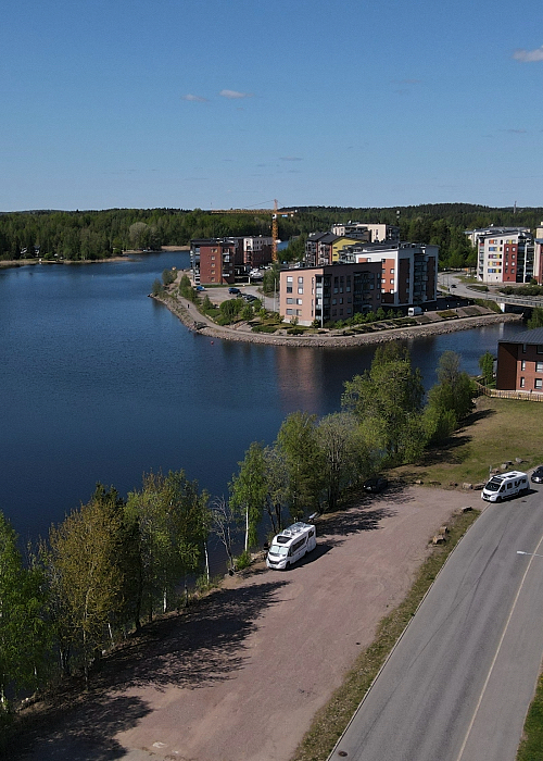 Matkailuauto parkissa Lappeenrannassa järven rannalla. Toiselle puolella vieressä tie.