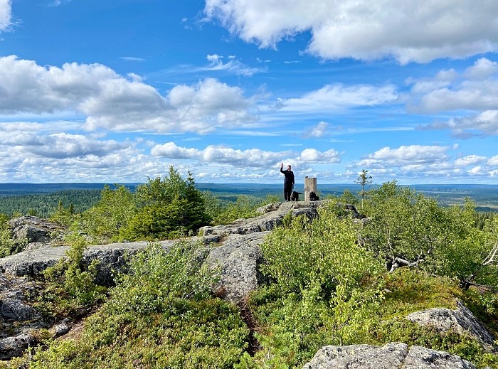 Pyhityksen huipulla mies ja koira. Maisemat avautuvat laajasti.