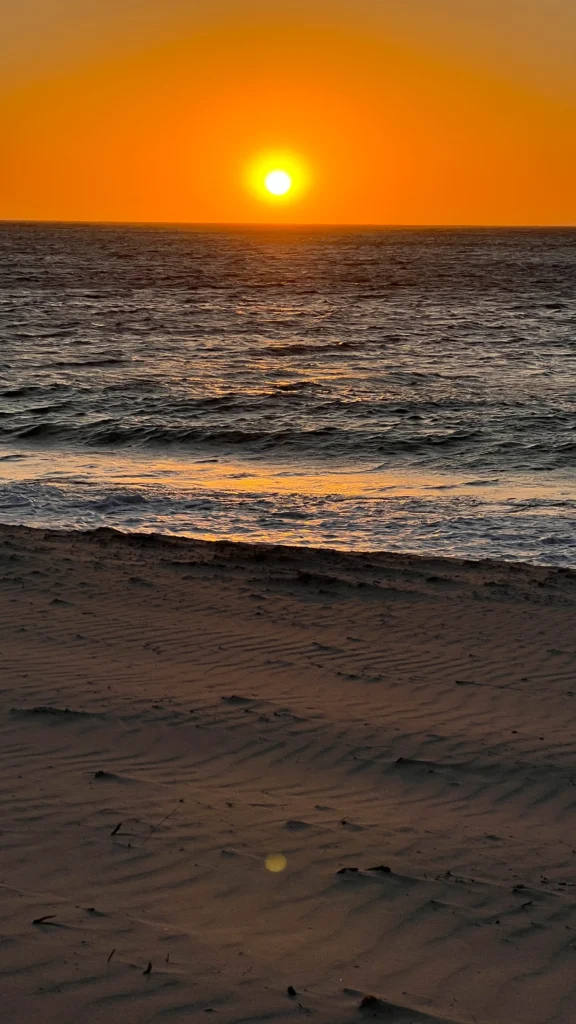 Auringonlasku Sandy Cape Recreation Park rannalla.