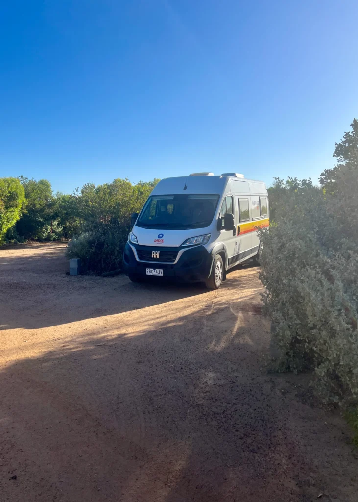 Retkeilyauto Coro Parkin lerintäalueen parkissa puska-aita ympärillä.