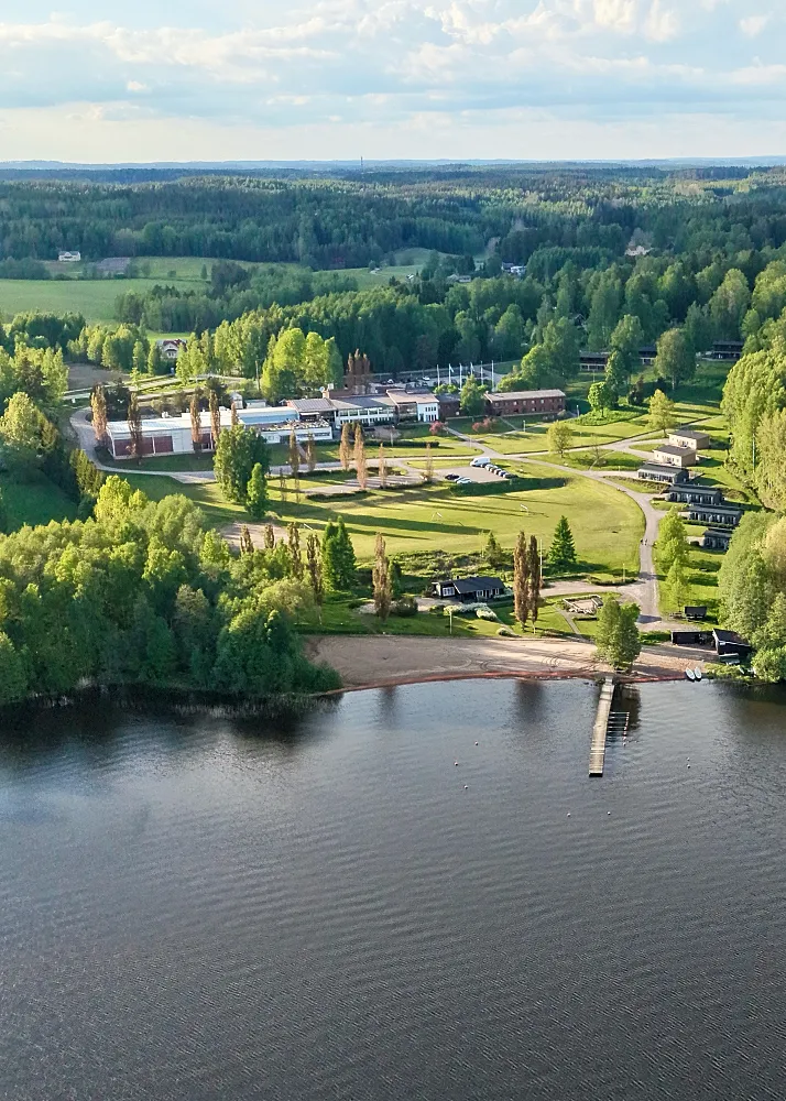 Lohja Spa yläilmoista kuvattuna. Taustalla hotellirakennus, oikealla  rivissä rantatalot ja edessä hiekkaranta laitureineen.